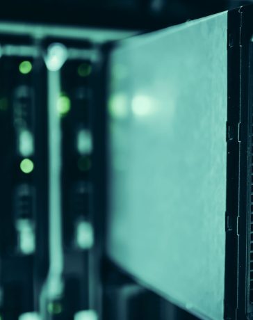 Racks de servidores em um moderno data center, iluminados em tons de azul.
