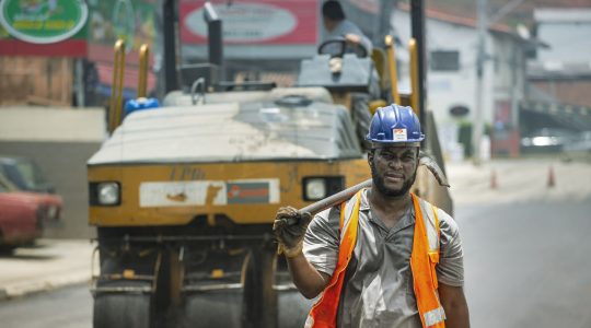 Trabalhador usando capacete e equipamentos de segurança atua em uma obra viária urbana em Cotia, no Brasil