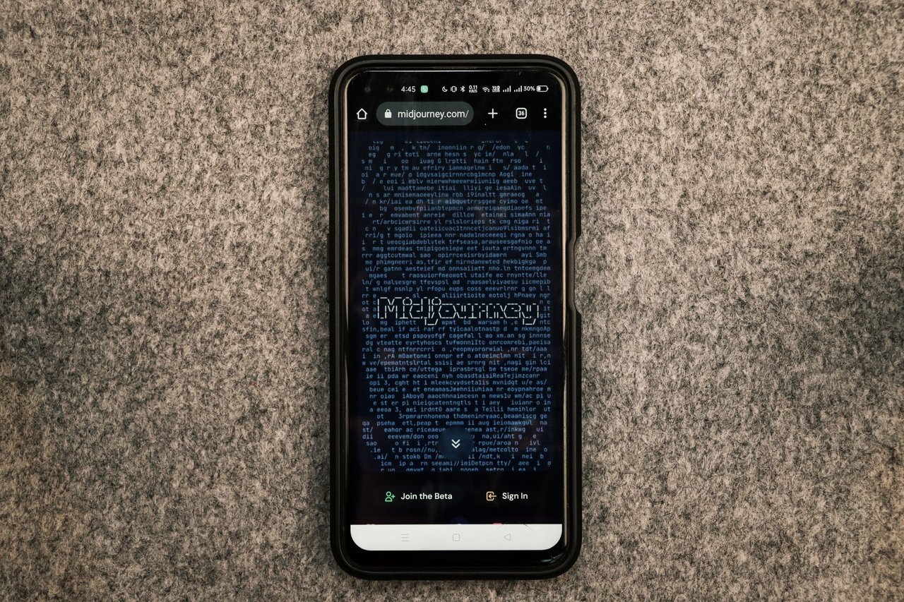 Smartphone exibindo o site Midjourney, plataforma de geração de imagens por inteligência artificial, sobre uma superfície cinza