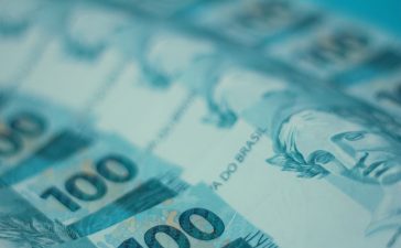 Cédulas de 100 reais brasileiras dispostas em detalhe.