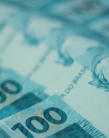 Cédulas de 100 reais brasileiras dispostas em detalhe.