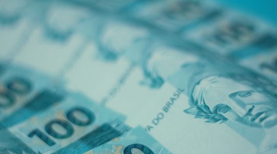 Cédulas de 100 reais brasileiras dispostas em detalhe.