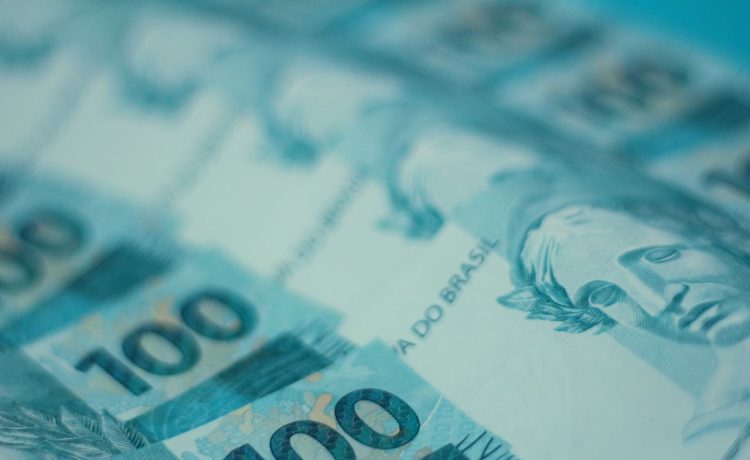 Cédulas de 100 reais brasileiras dispostas em detalhe.