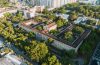 Vista aérea de um campus universitário histórico, cercado por áreas verdes, no Rio de Janeiro.