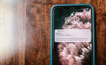 Smartphone exibindo uma notificação de alerta contra fraude sobre uma superfície de madeira.