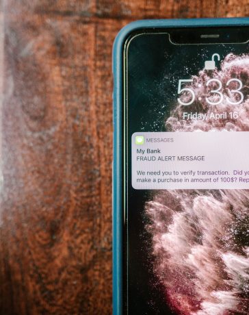 Smartphone exibindo uma notificação de alerta contra fraude sobre uma superfície de madeira.