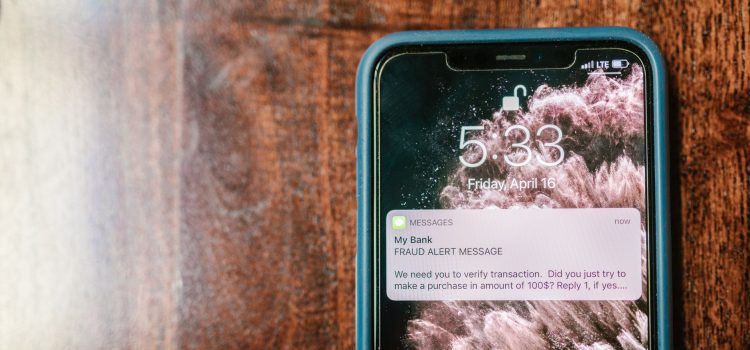 Smartphone exibindo uma notificação de alerta contra fraude sobre uma superfície de madeira.