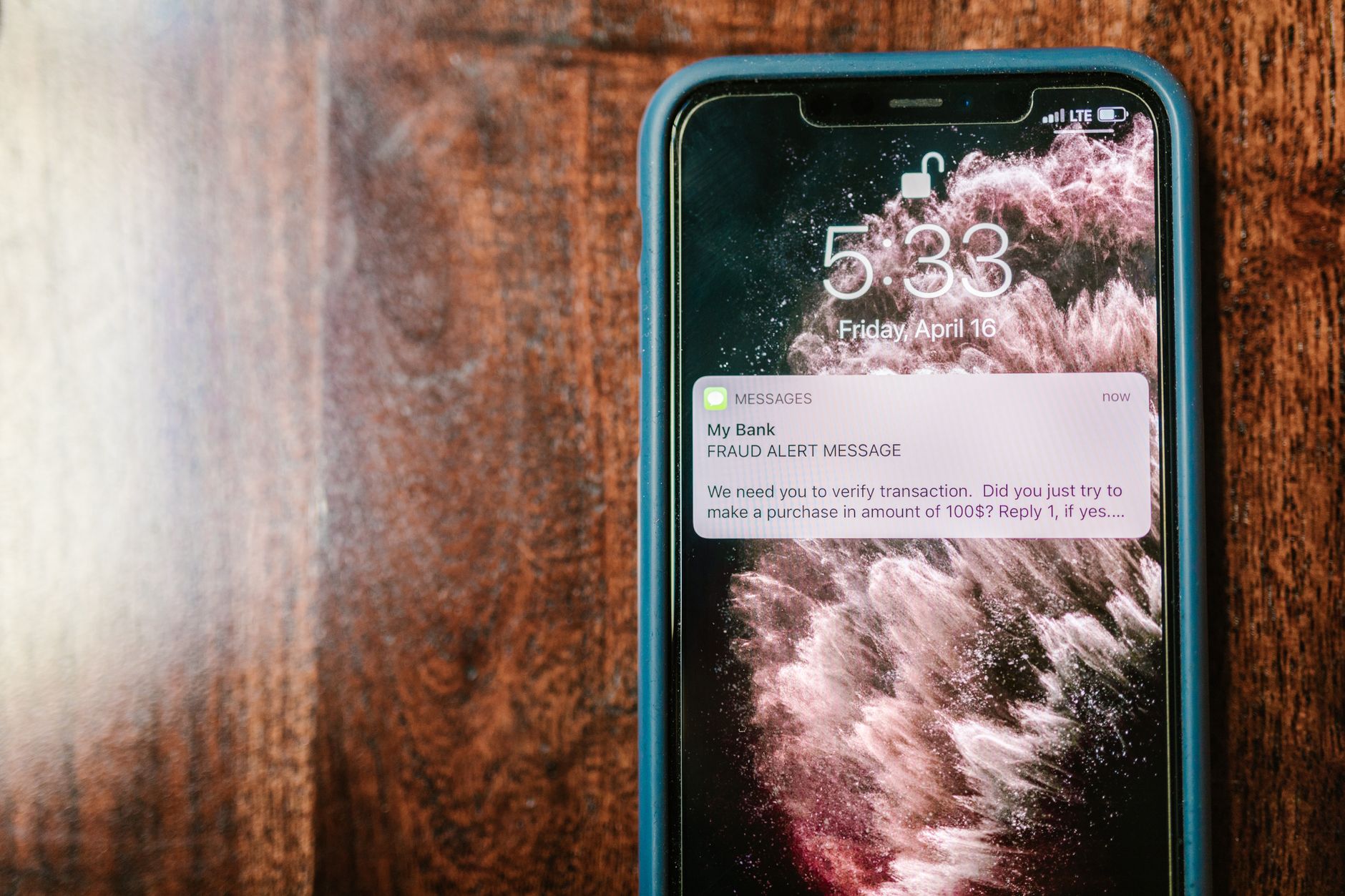 Smartphone exibindo uma notificação de alerta contra fraude sobre uma superfície de madeira.